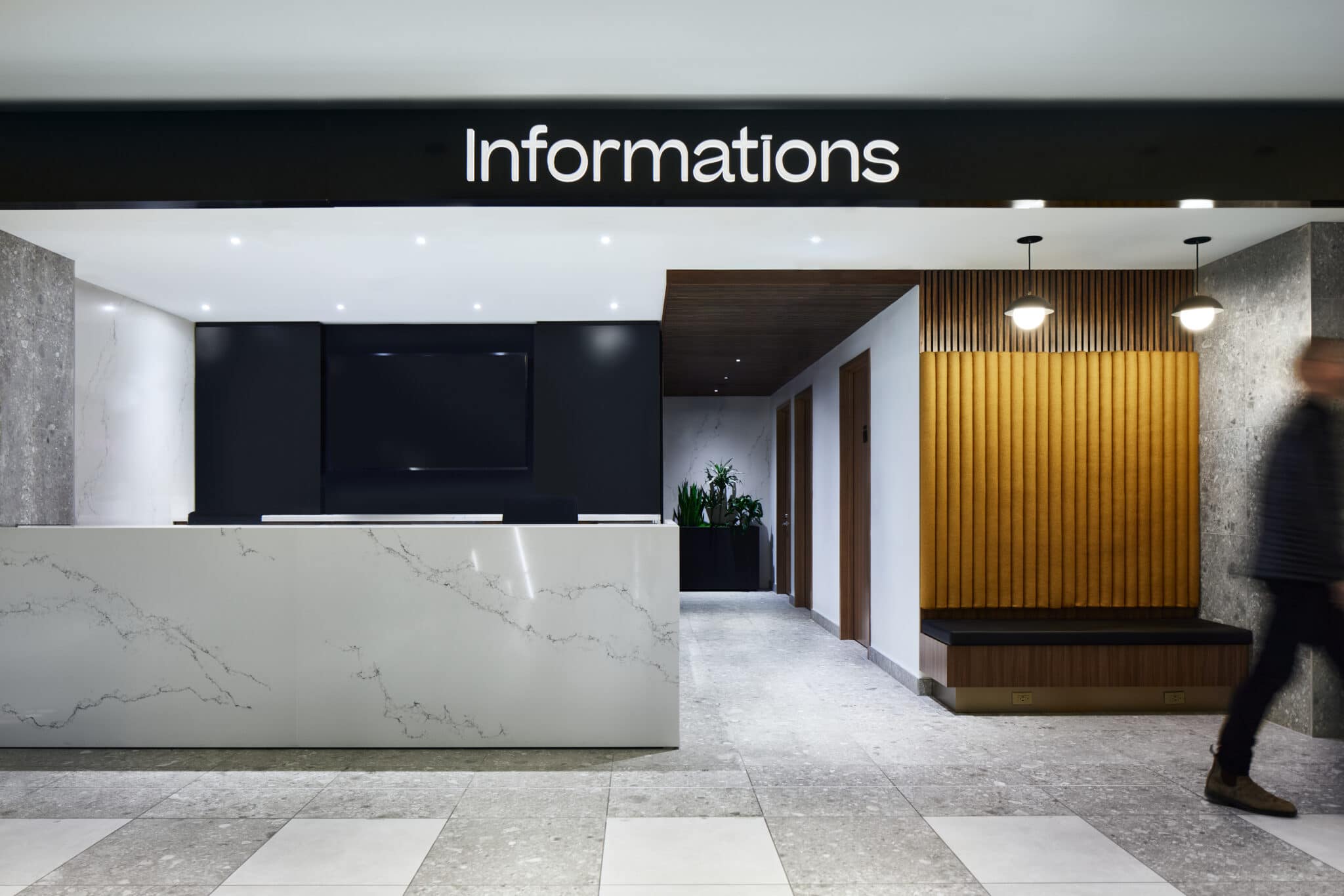 Projet de design - Vue en angle du comptoir d'accueil de l'espace Service à la clientèle à la Place Ville Marie de Montréal par VAD Designers d'intérieur commercial.